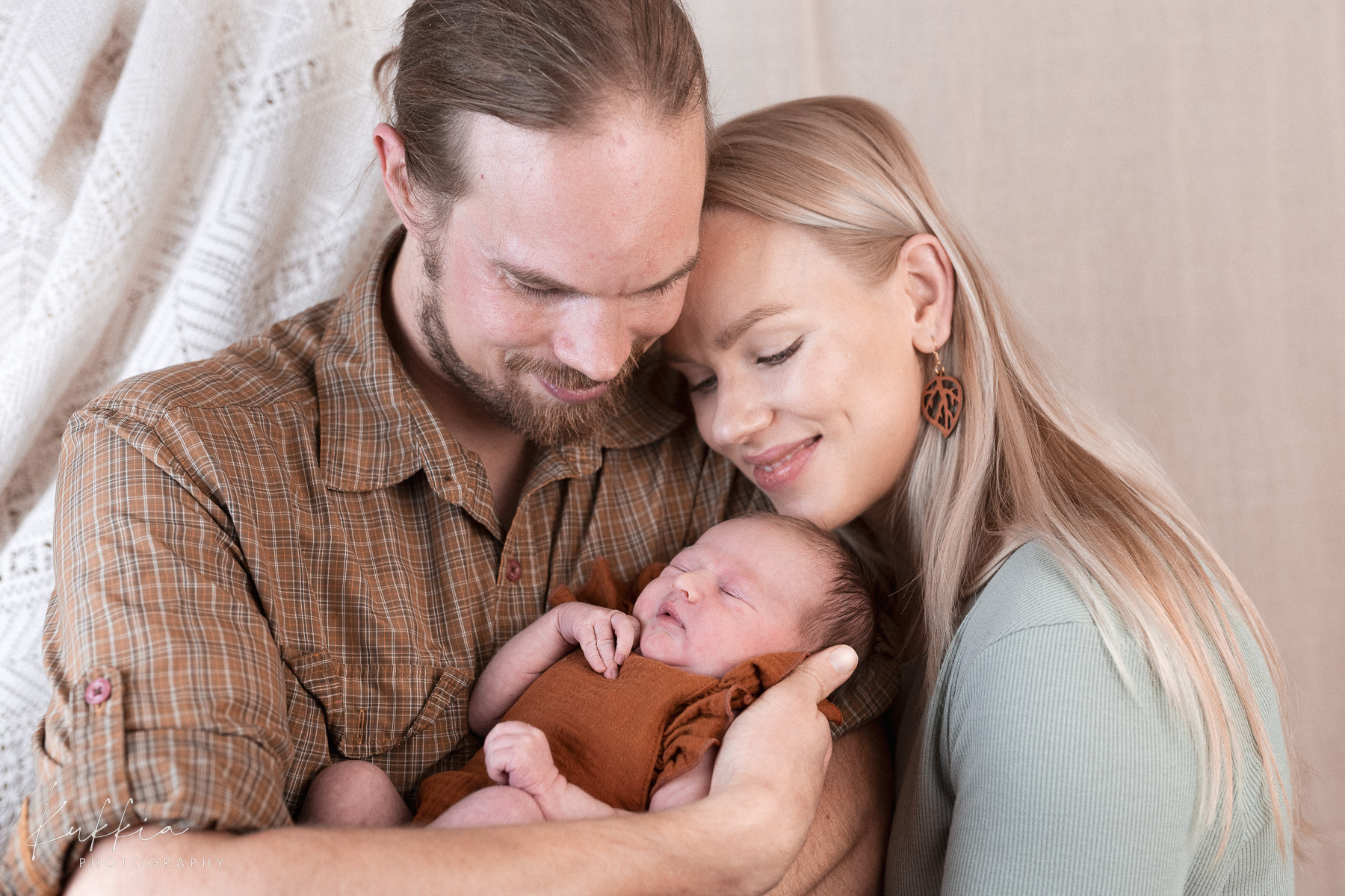 newborn-perhekuvaus-rauhallinen-hetki-vauva Vanhemmat pitävät sylissään nukkuvaa vastasyntynyttä vauvaa rauhallisessa kuvassa